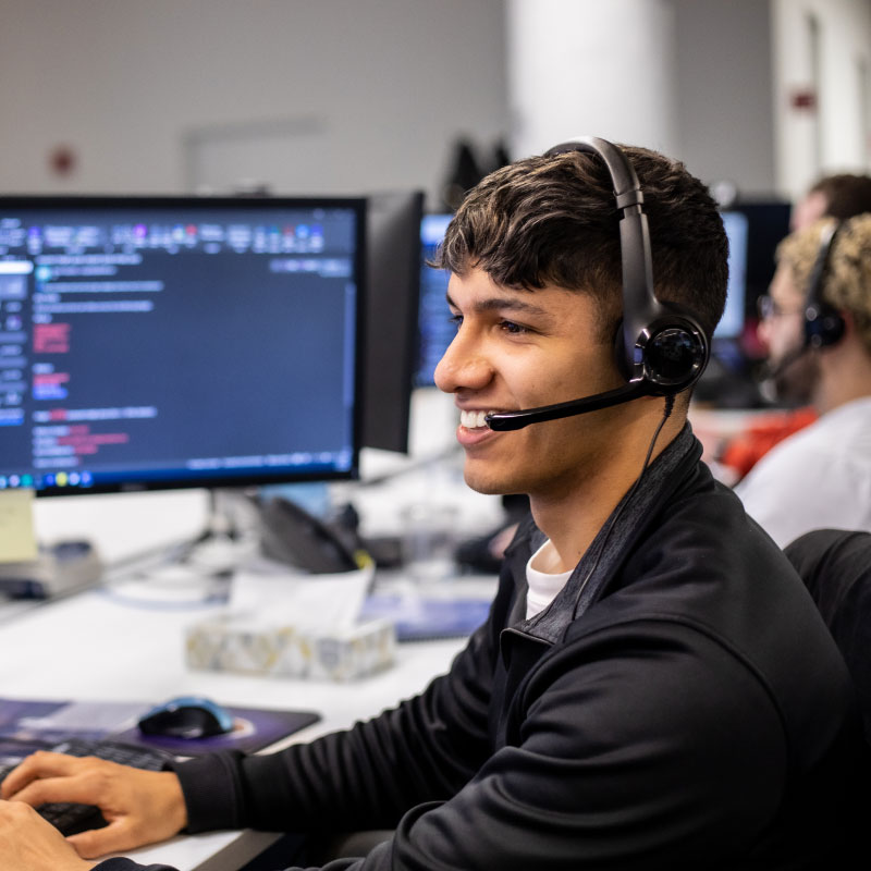 An Echo employee with a headset on sitting at their workstation looking at the computer screen.