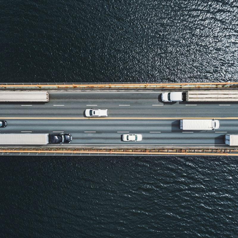 Aerial view of bridge over body of water with trucks and cars.