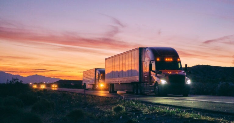 Semi trucks driving on highway at night.