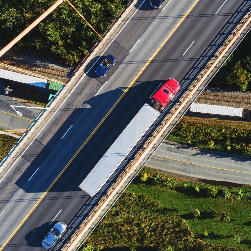 Red semi truck driving down interstate.