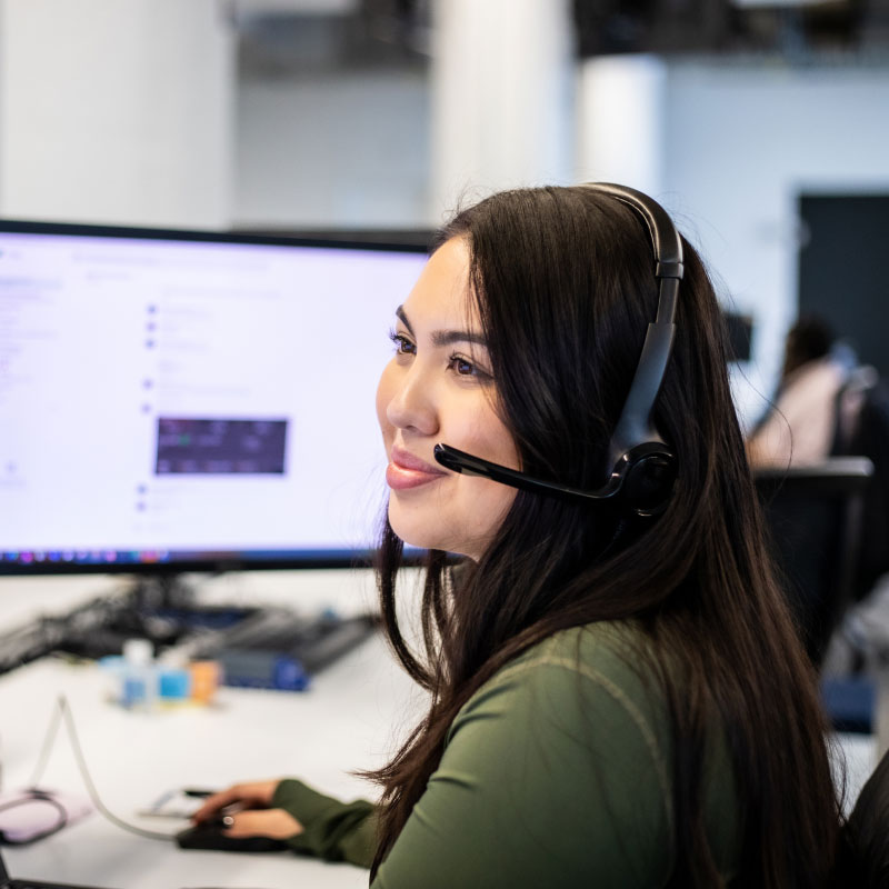 An Echo employee smiling at their desk at work while providing shipping clients with transportation solutions.