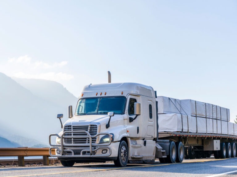 A semi truck transporting cargo on a flat bed semi trailer on the narrow road along the Columbia River.