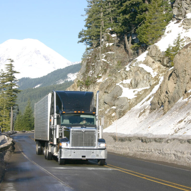 A blue semi truck driving down a road.