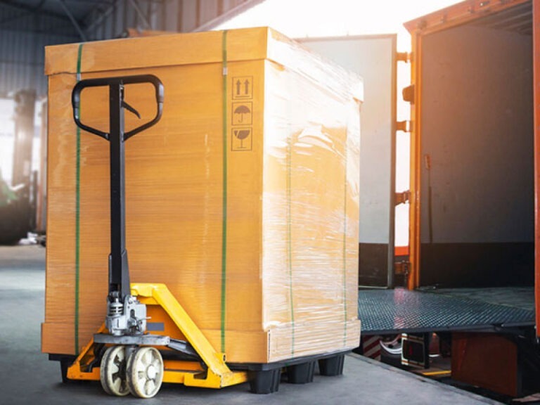 A shipping container properly packaged waiting to be loaded onto a semi's truck bed.