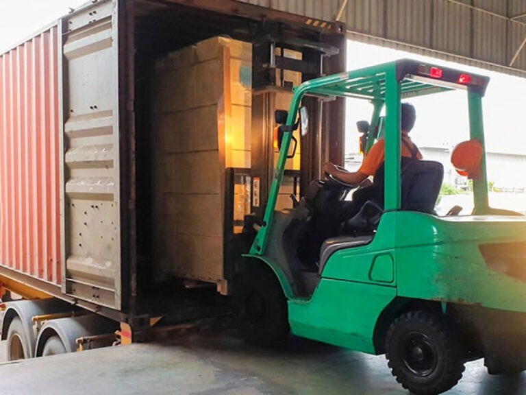 Multiple properly packed shipping containers being loaded into a semi's truck bed.