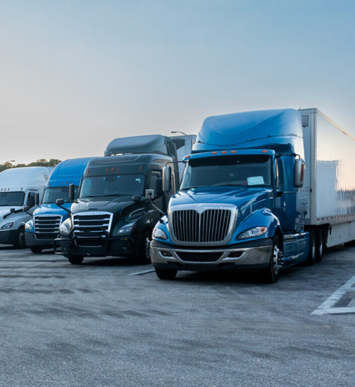 Semi trucks parked in a row at a truck stop.