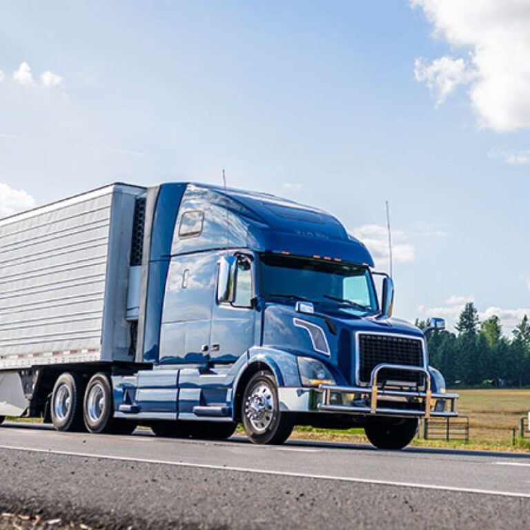 A blue semi truck driving on the road.