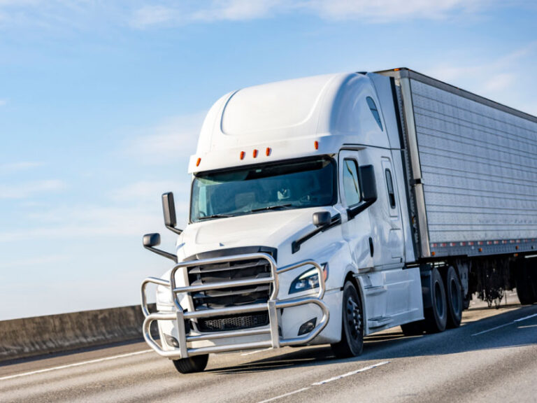 White semi truck transporting cargo down the highway during the day time.