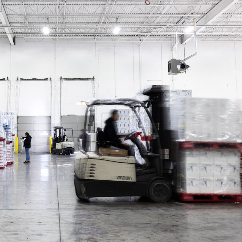 Warehouse employees moving around freight in warehouse.