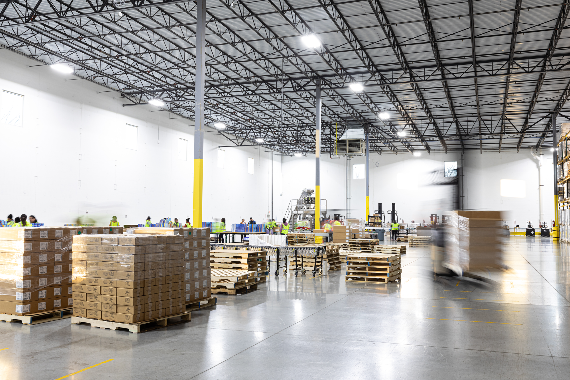 Warehouse assembly lines and warehouse workers moving pallets of shipments.