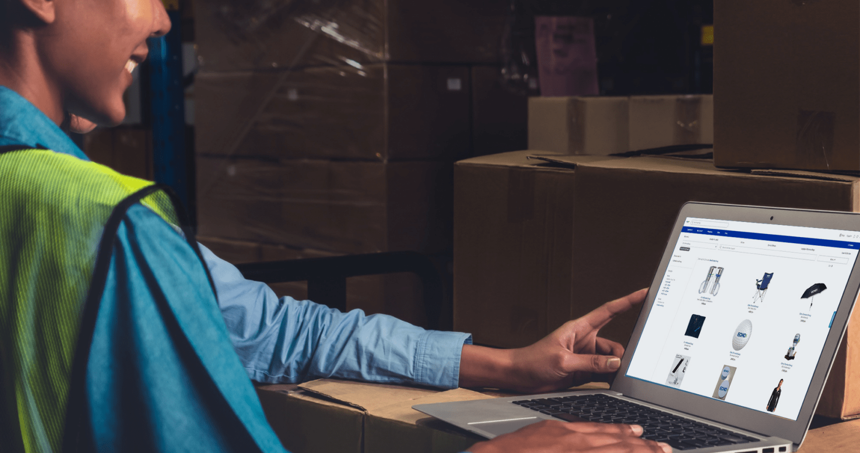 Factory worker using laptop on top of boxes