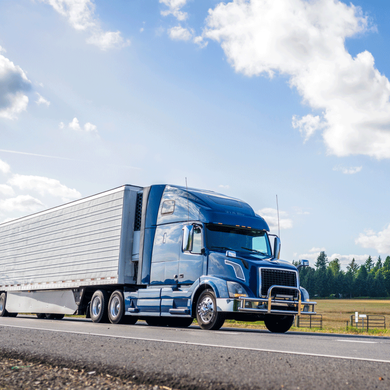 Blue truck driving down summer highway.