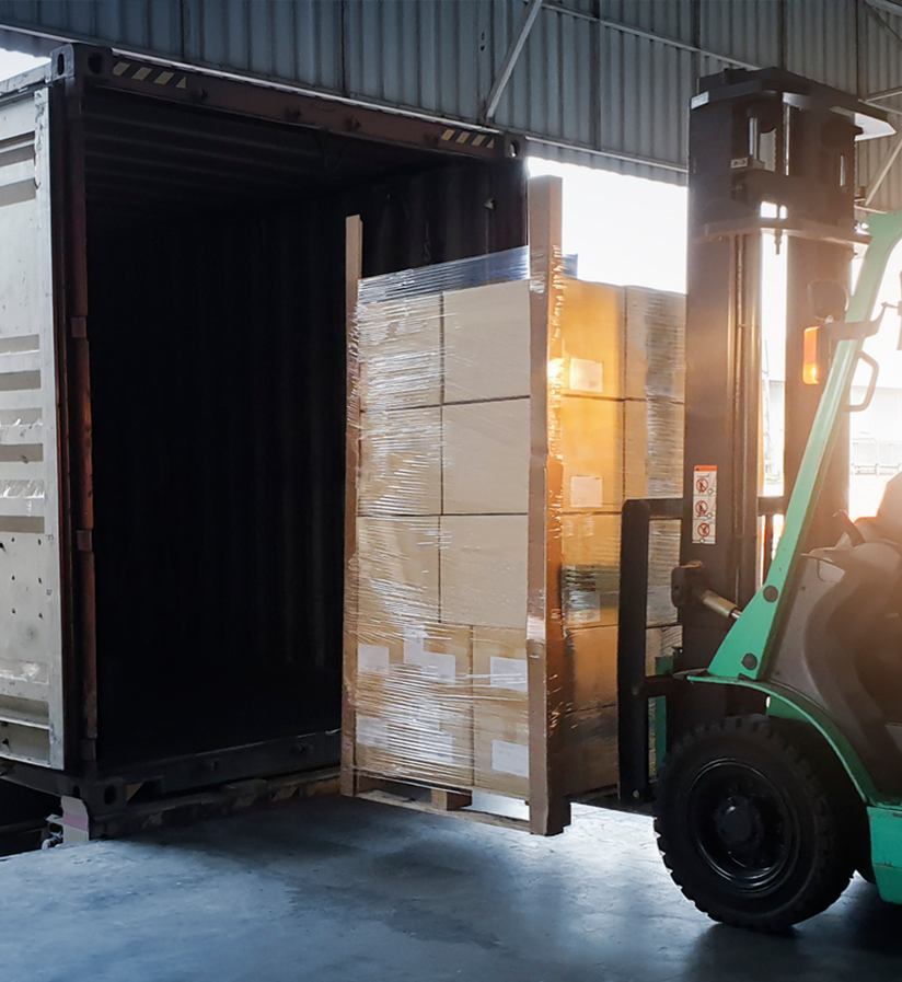 A forklift carefully loading a shipment into a semi truck.