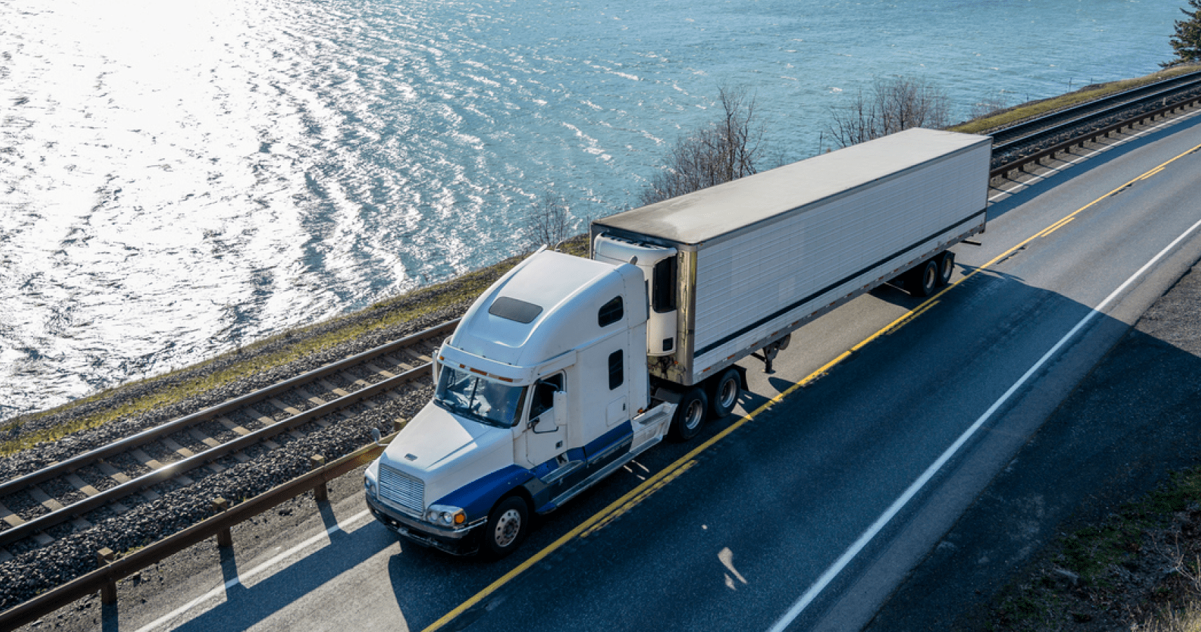 A Temp-Controlled semi truck driving along the Columbia River transporting cargo.