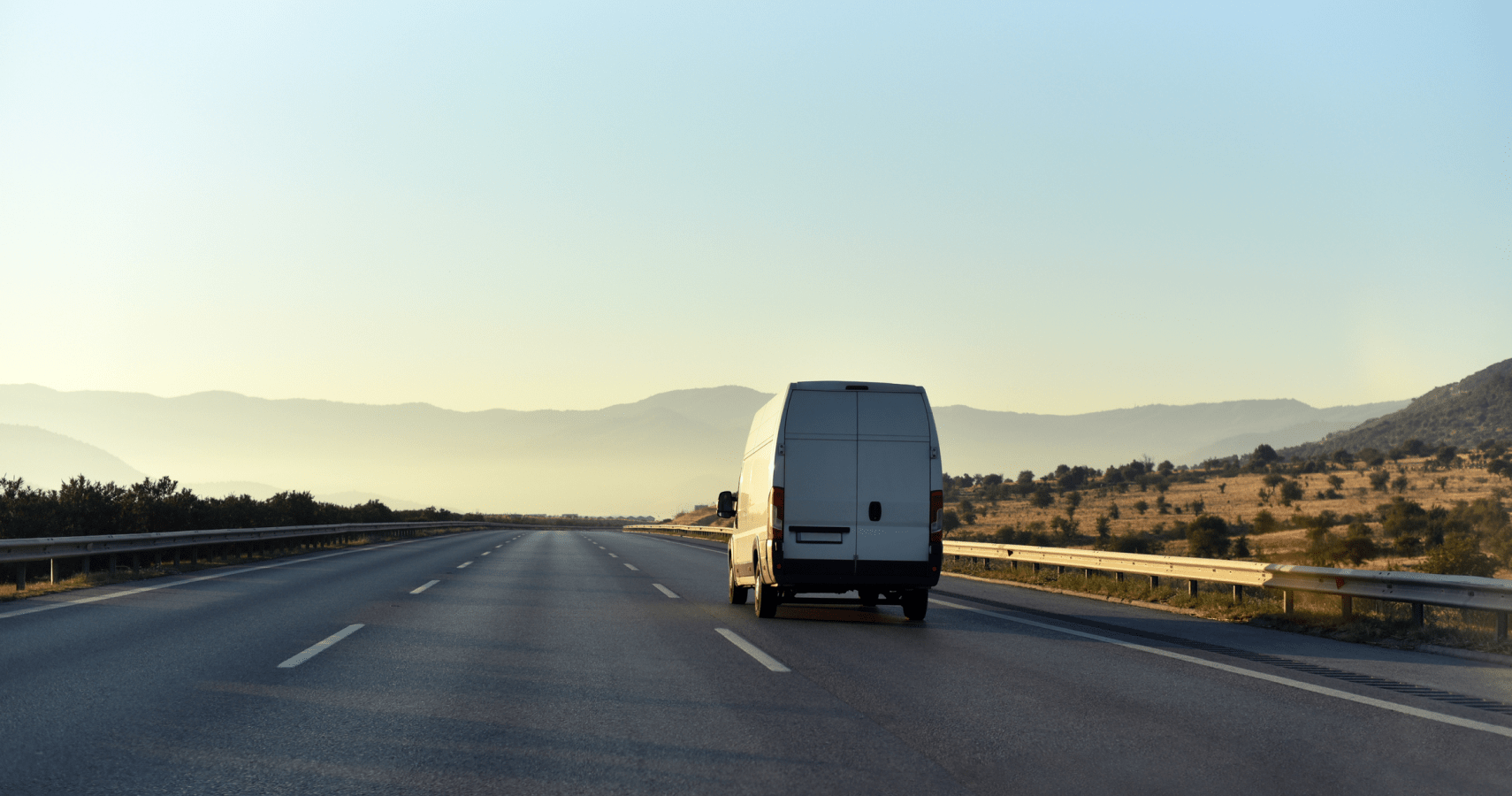 A white small parcel carrier van driving down a highway to deliver clients packages.